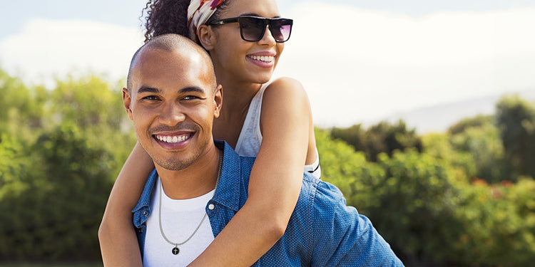 Glückliches Paar im Freien - Mann trägt silberne Halskette mit rundem Gravur-Anhänger