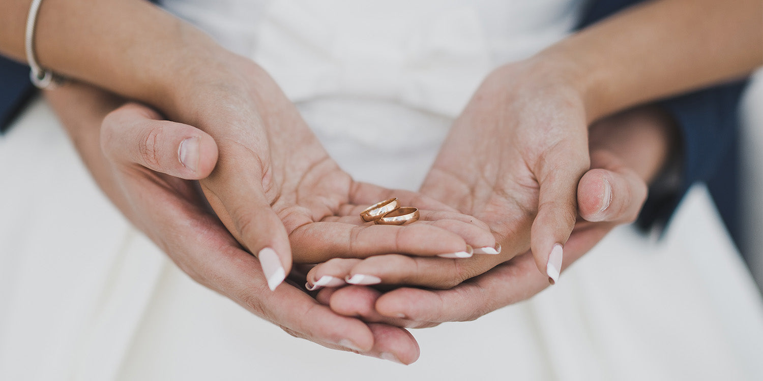 Paar hält goldene Eheringe in den Händen - klassische Trauringe von Rhomberg