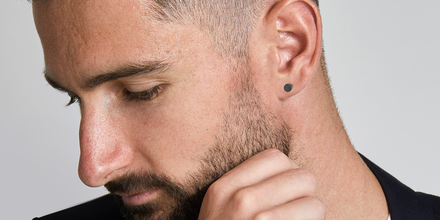 Mann mit Bart trägt schwarze runde Ohrstecker