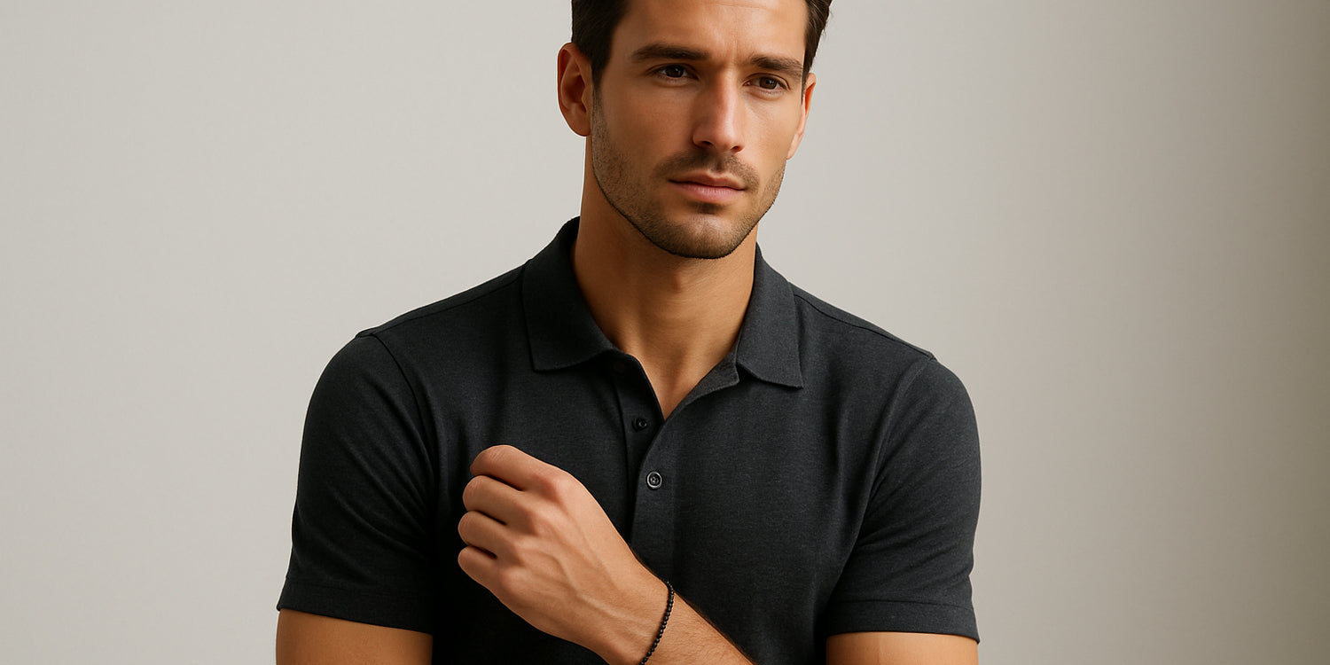 Sportlicher junger Mann trägt dunkles Poloshirt und ein Armband vor neutralem Hintergrund